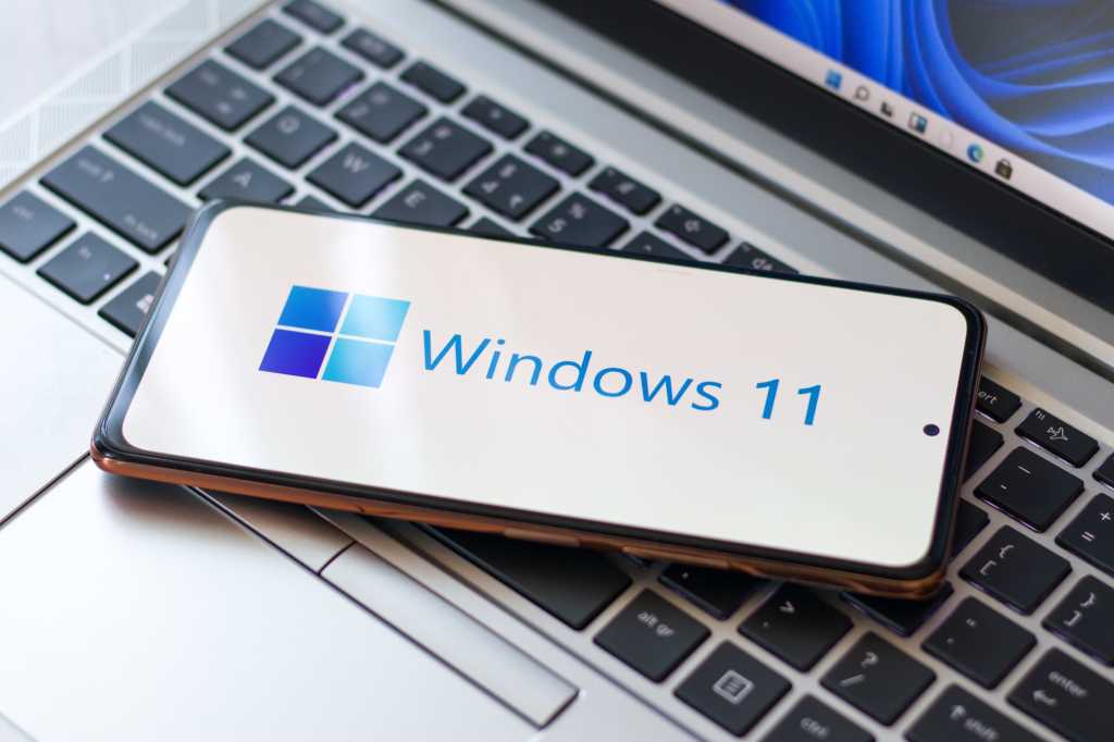 Windows 11 Logo On Phone Sitting On Laptop Keyboard Hero 2.jpg