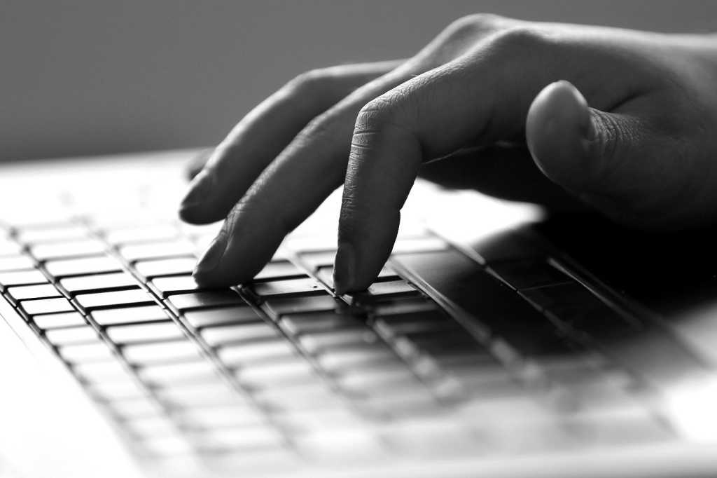 Black And White Photo Of Hand Using A Laptop Keyboard.jpg