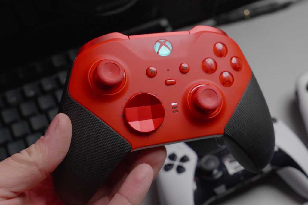 Red wireless xbox gaming controller in hand held over desk alternate view.jpg